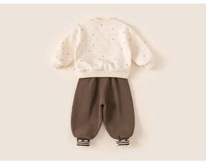 Close-up of cream sweatshirt with heart prints and brown pants with lace hem