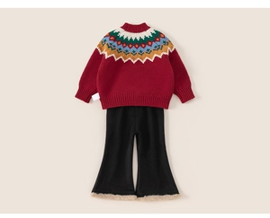 Détail d'un pull festif rouge à motif Fair Isle et pantalon évasé noir avec bordure en fourrure