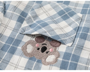 Close-up of blue plaid cotton shirt featuring a cute koala embroidery on the pocket
