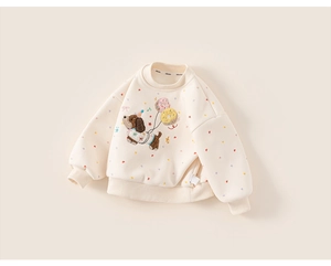 Detailed close-up of cream sweatshirt with cute embroidered dog and colorful heart dots