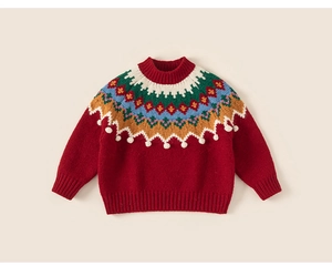 Détail d'un pull en tricot festif rouge avec motif nordique Fair Isle et pompons blancs