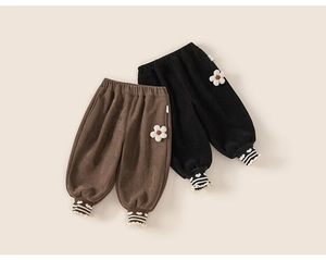 Détail du pantalon en velours côtelé doublé avec patchs de fleurs et poignets rayés