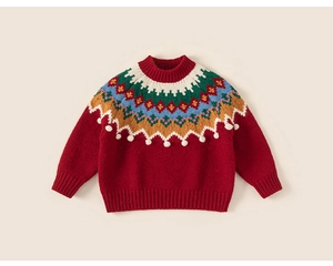 Détail du pull rouge pour enfant avec motif jacquard nordique et ornements de pompons 3D