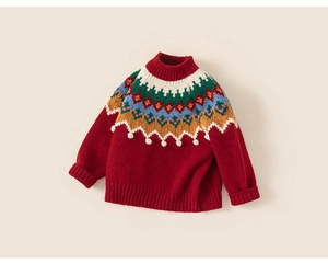Détail d'un pull rouge pour enfant avec motifs jacquard colorés et petits pompons blancs doux