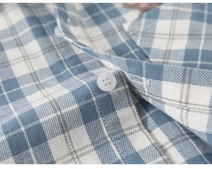 Detailed close-up of blue plaid shirt fabric texture and white resin buttons