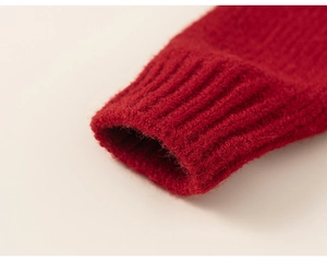 Gros plan de la manche d'un pull en maille rouge montrant la texture des poignets