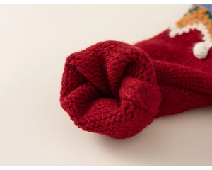 Gros plan d'une manche de pull en maille rouge avec motifs jacquard colorés
