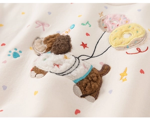 Detailed close-up of 3D dog puppy embroidery on warm cream white toddler sweatshirt