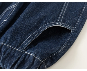 Close-up of deep blue denim pants with white double stitching and elastic hem detail