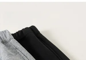 Gros plan des tailles élastiques sur pantalons en maille gris et noir pour enfants
