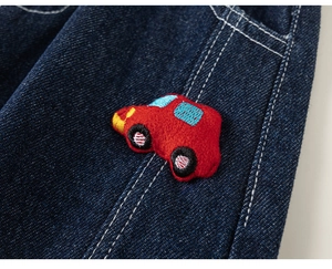Detail of red car embroidery patch on dark blue denim fabric for boys clothing