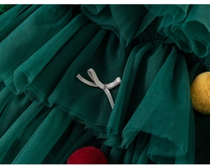 Détail de maille multicouche vert foncé avec nœud satiné et pompons colorés