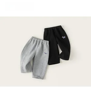 Détail de pantalons en coton gris et noir pour enfants avec broderie de chien colorée
