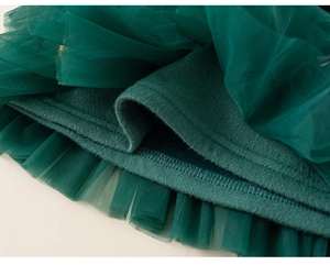 Détail du tissu en tulle multicouche vert foncé avec couture d'ourlet sur pull fille