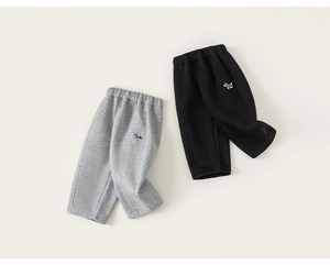 Détail de joggings pour enfants en gris et noir avec une broderie de chiot précise
