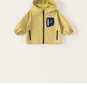 Détail d'une veste coupe-vent jaune pour garçon avec fermeture marine et poche de poitrine