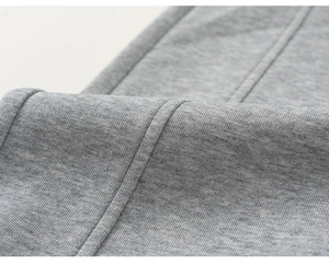 Gros plan sur la texture du tricot gris et les coutures propres du pantalon en coton