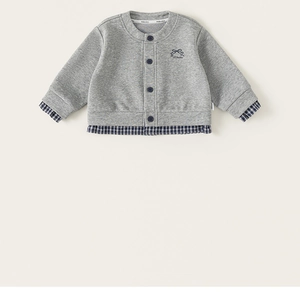 Close-up of grey knit cardigan featuring blue plaid patchwork and button details