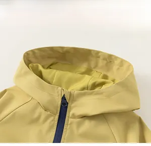 Détail d'une veste à capuche jaune coupe-vent avec fermeture éclair bleu marine contrastée