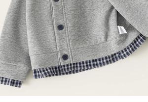 Detail of grey knitted cardigan with blue plaid patchwork and dark buttons for kids