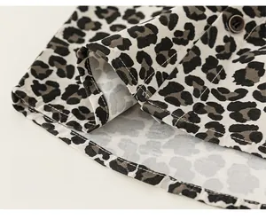 Detail of boys leopard print shirt showing loose hem and brown button design