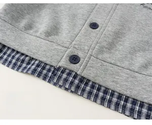 Detail view of girl's grey knit sweater with blue checkered hem and contrast buttons