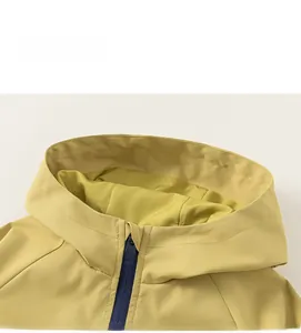 Détail de la veste à capuche jaune avec fermeture éclair bleu marine et tissu tissé