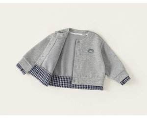 Detail of grey knit cardigan featuring blue plaid patchwork and bow embroidery