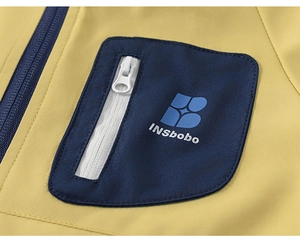 Gros plan sur la veste d'extérieur jaune avec poche de poitrine bleu marine et zip blanc