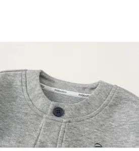 Detail of grey knit cardigan neckline with blue button and high-quality fabric texture