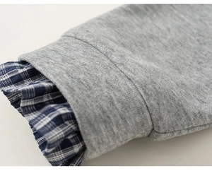 Close-up of grey knitted sleeve with blue plaid ruffle detail on girl's cotton jacket