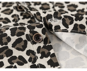 Detailed macro view of leopard print fabric with dark brown four-hole button on kids' shirt