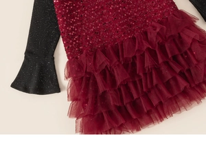 Detail of girls red sequin dress featuring layered mesh skirt and glitter sleeves