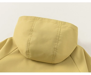Détail d'une veste à capuche jaune vif montrant le tissu coupe-vent et les coutures
