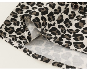 Macro detail of leopard print shirt hem with high-quality stitching and dark brown button