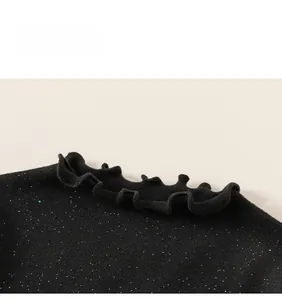 Detail of children's black glitter top featuring a stylish ruffled lettuce edge neckline