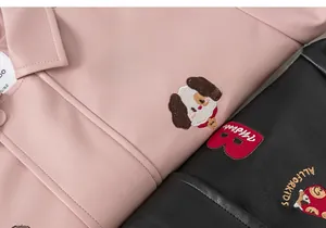 Detailed view of pink and black faux leather jackets with cute cartoon puppy embroidery