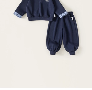 Detail of navy boy's two-piece set featuring faux-layered plaid cuffs and drawstring waist