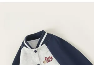 Detail of kids baseball jacket showing Lucky Bear embroidery and snap button closure