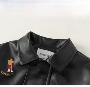 Detail of kids black PU leather jacket lapel with festive embroidery and brand neck label