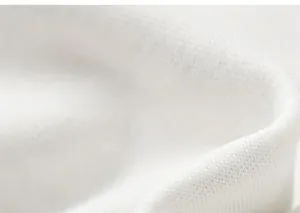 Detailed close-up of soft white knitted fabric showing fine textile texture and quality