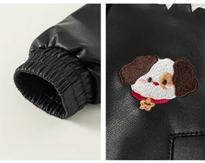 Detail view of elastic cuffs and cartoon puppy embroidery on kids black faux leather jacket
