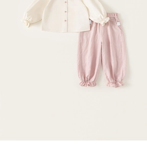 Detail of baby girl outfit with pink floral embroidery and ruffled hem on trousers