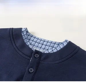 Detail of navy knit polo neckline with plaid inner lining and dual button closure