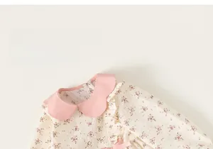 Dettaglio di un abito floreale da bambina con colletto a petalo rosa e tessuto a pois