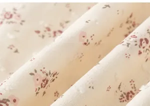 Dettaglio del motivo floreale con trama morbida e base crema sull'abito da bambina