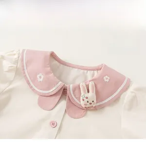 Detail of baby blouse with pink doll collar, flower embroidery and cute bunny doll decor