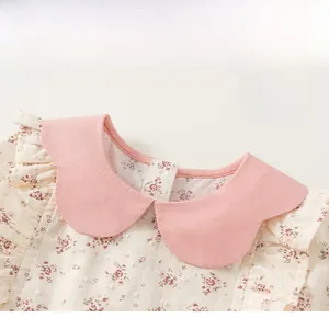 Dettaglio del vestito a fiori da bambina con colletto rosa a contrasto e balze sulle spalle