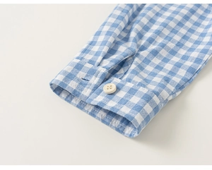 Detail of blue and white gingham shirt cuff with premium white button and clean stitching