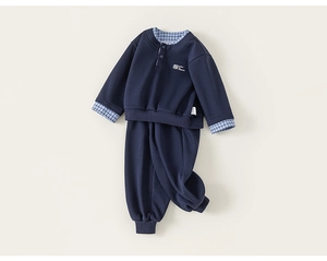 Detail of navy two-piece kids set with blue plaid layers and fine white embroidery